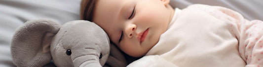 a baby sleeping with an elephant plush toy