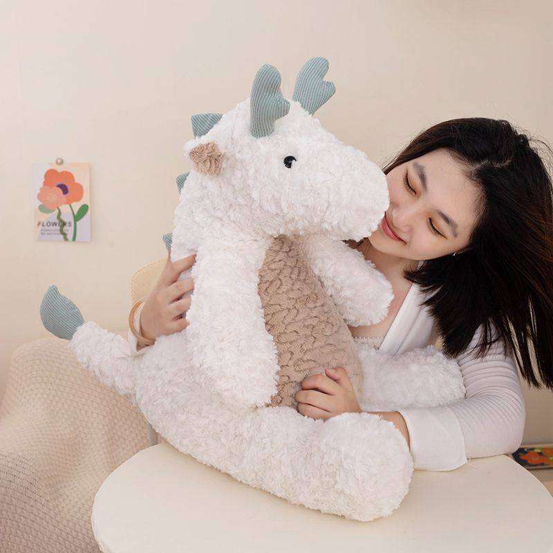Girl holding a giant white dragon stuffed animal