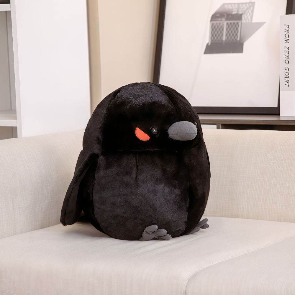 A black crow stuffed animal sitting on a couch.