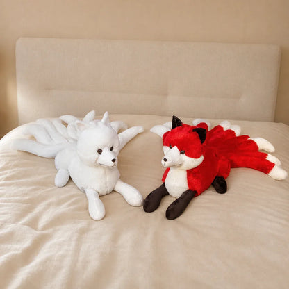 White and Red Nine-Tailed Fox Stuffed Animals on a Cozy Bed