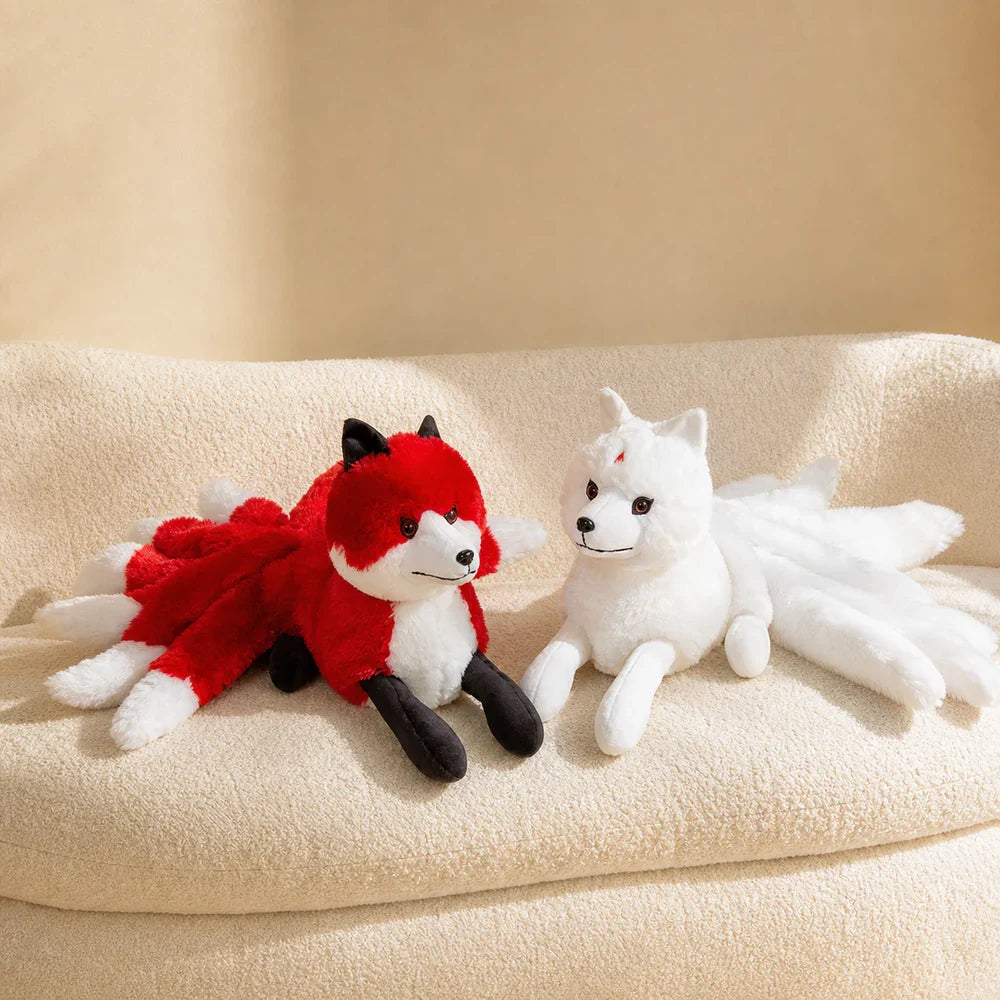 White and Red Nine-Tailed Fox Stuffed Animals on a Cream Sofa