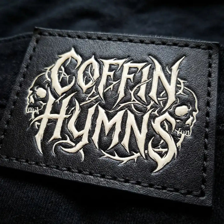 Black leather patch with 'Coffin Hymns' design on a dark background