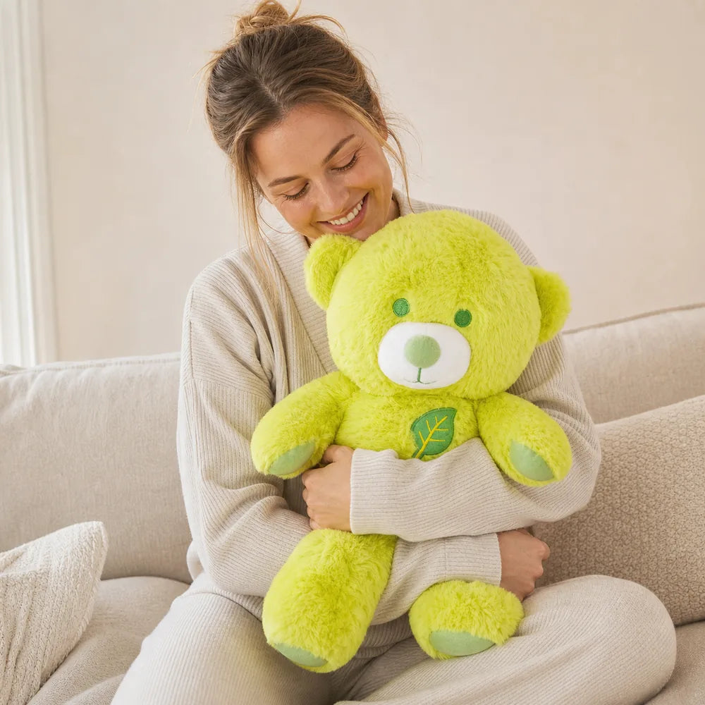 Woman hugging a large lime green leaf teddy bear plush on a cream sofa
