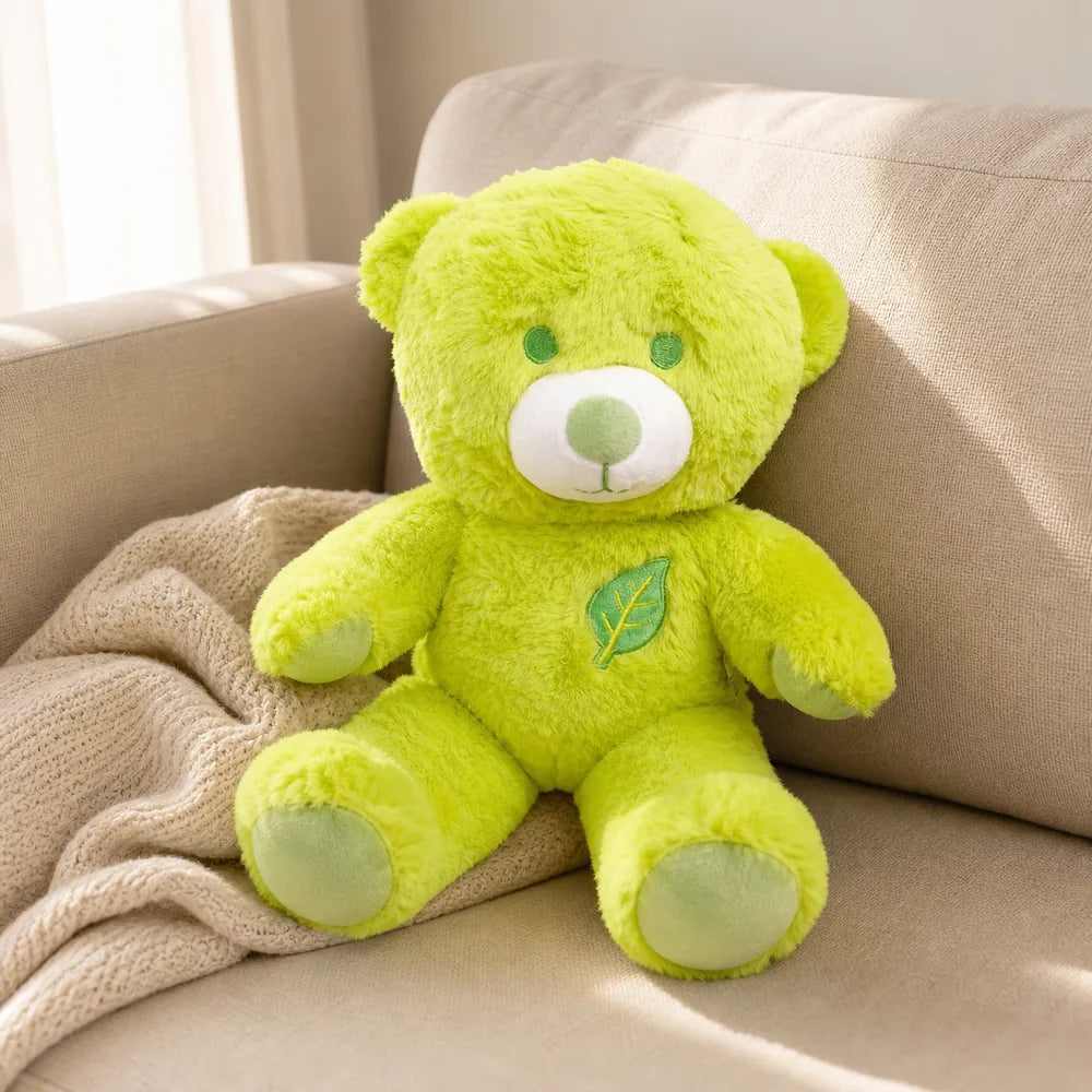Lime green leaf teddy bear plush relaxing on a warm beige sofa