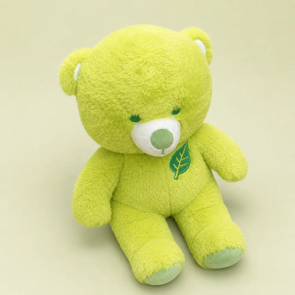 Lime green leaf teddy bear plush in an angled seated view on a soft sage studio backdrop