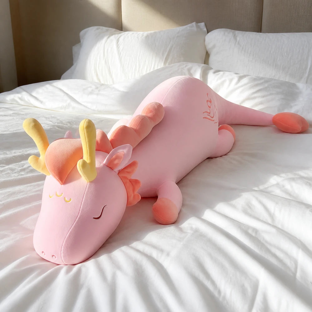 Pink Lovely Herbivore Dragon Plush Resting on a Bright White Bed