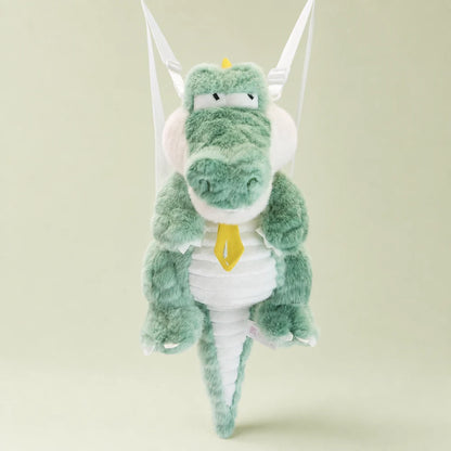 Mint green crocodile plush backpack with visible white shoulder straps on a sage studio backdrop