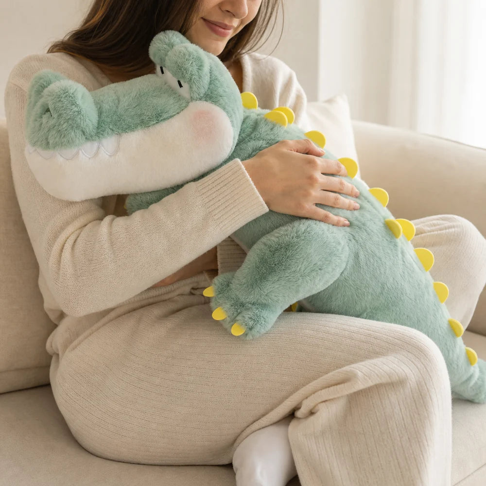 Woman hugging a large mint green crocodile long pillow plush on a cream sofa