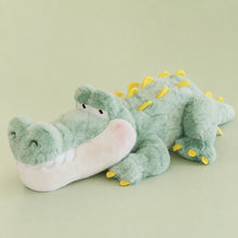 Mint green crocodile long pillow plush with yellow back spikes on a sage studio backdrop