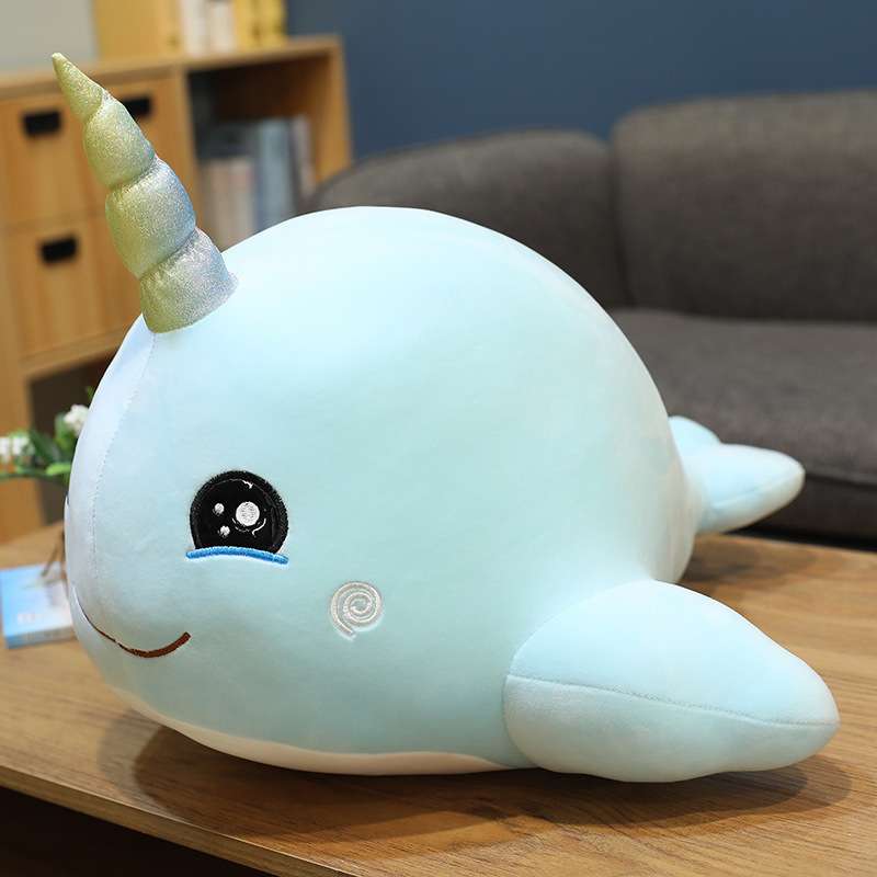 narwhal plushies, blue, sitting on a bed. 