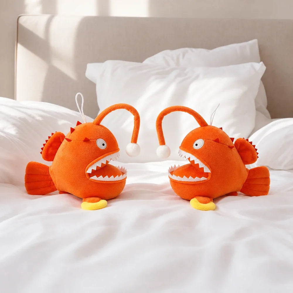 Two Cartoon Orange Anglerfish Plush Toys on a Bed