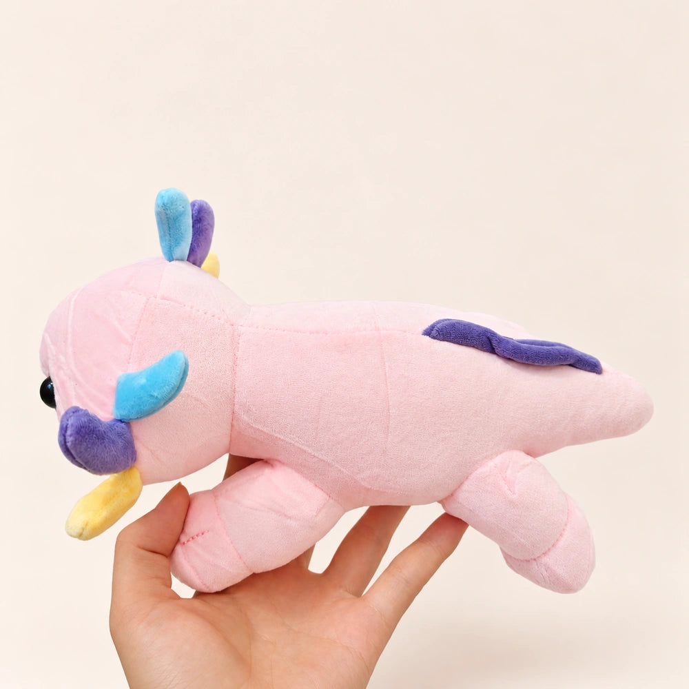 Side view of the Pastel Gills axolotl plush held in one hand, showing colorful gills and a purple tail fin.