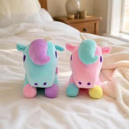 Pink and turquoise pastel unicorn plush toys on a cozy bed