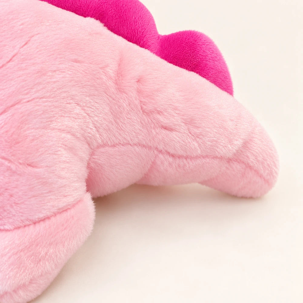 Close-up of the pink axolotl plush showing short-pile fabric, stitched seams, and the bright pink fin.
