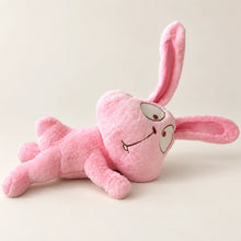 Pink bunny plush lying on its side with long ears and an embroidered face.