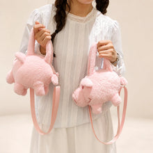 Pink pig plush purse held by a model