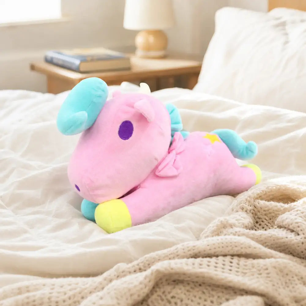 Pink pastel unicorn plush toy on a cozy bed