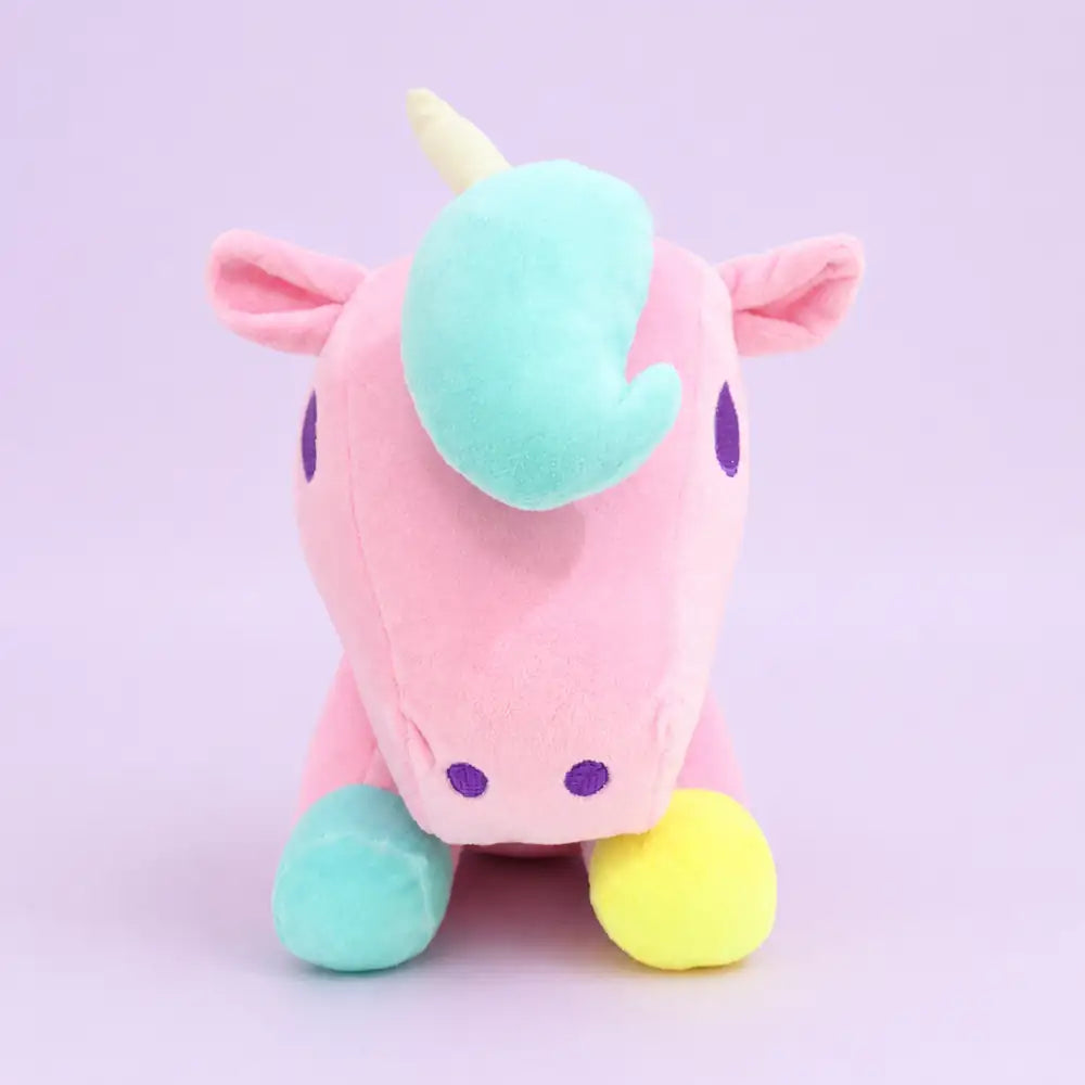 Pink pastel unicorn plush toy front view on a lavender studio background