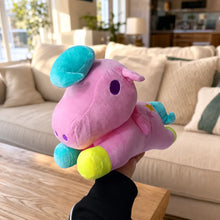 Pink pastel unicorn plush toy held in a warm living room