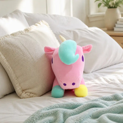 Pink pastel unicorn plush toy by soft bedroom pillows