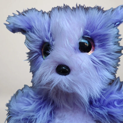 Angled close-up of the purple mermaid dog plush with a fluffy muzzle and black nose.