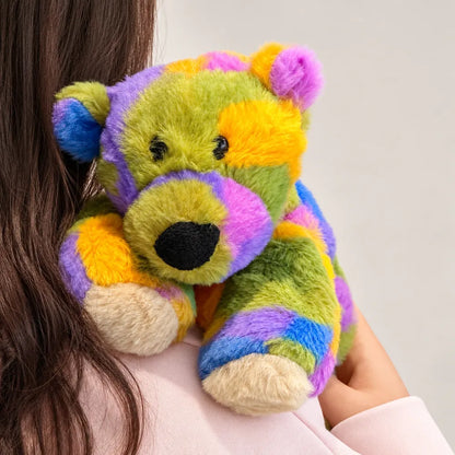 Close-up of a rainbow bear plush being hugged, showing its black nose and soft faux fur.