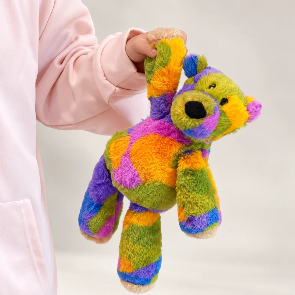 Rainbow bear plush held by one raised arm, showing its colorful body and long legs.