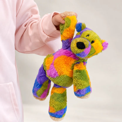 Rainbow bear plush held by one raised arm, showing its colorful body and long legs.
