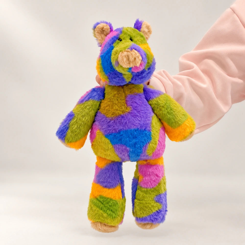 Rainbow pig plush with a cream snout, purple belly, and multicolored arms and legs.