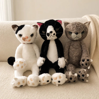 Black White and Gray Scowling Cat Plushes on a Cream Sofa