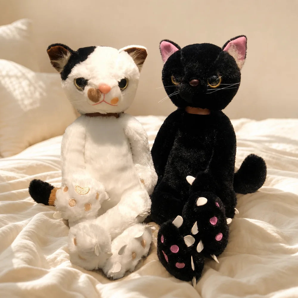White and Black Scowling Cat Plushes on a Cozy Bed