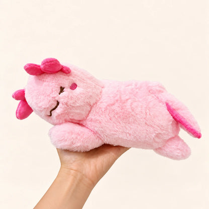 Handheld side view of the fluffy Sleepy Pink axolotl plush with an embroidered sleepy expression and darker pink gills.